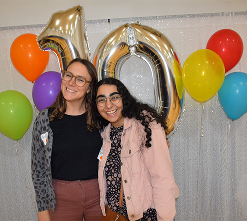 two young people with arms around each other in front of balloons