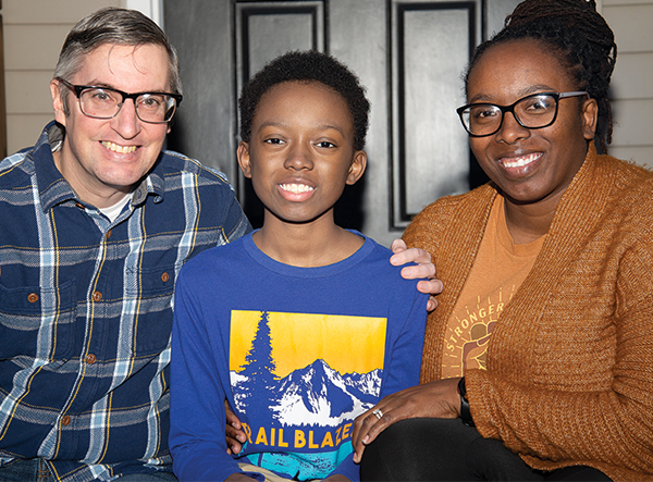 Donte sits between his parents in front of a door