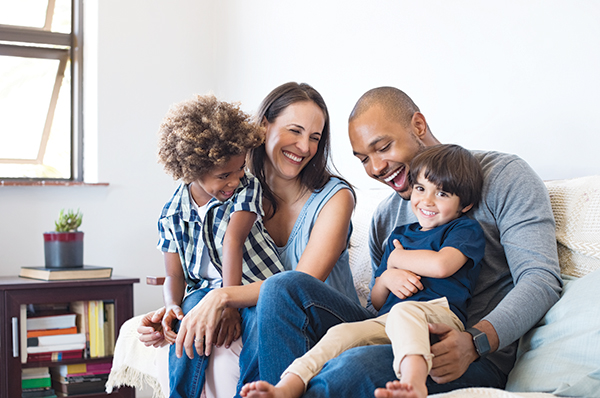 family of four sitting on couch and laughing