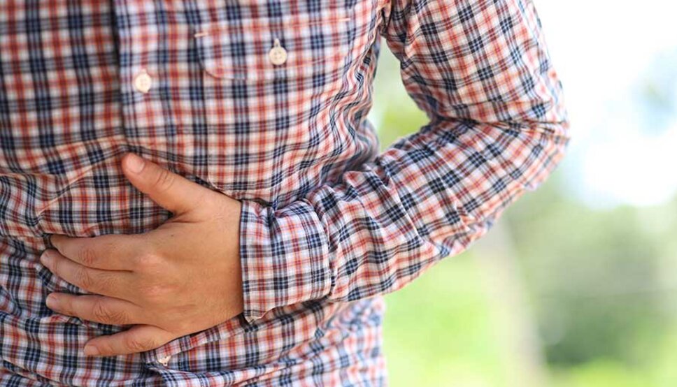 adult in plaid shirt holding stomach
