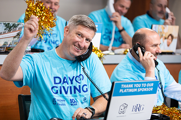 phone bank volunteer in blue shirt waves pom pom after receiving donation