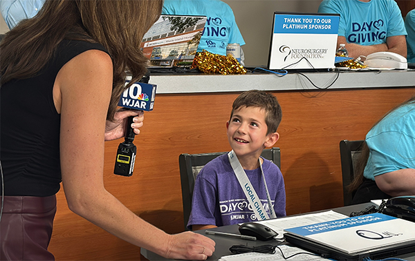 newswoman speaks with champion child Jasper while he answers phones