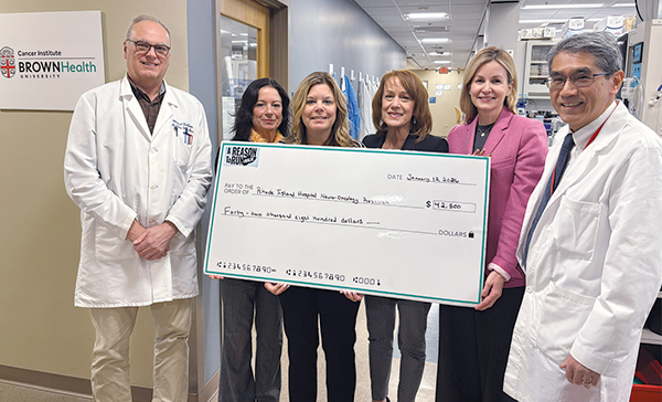 Four women present check to two doctors at the cancer institute