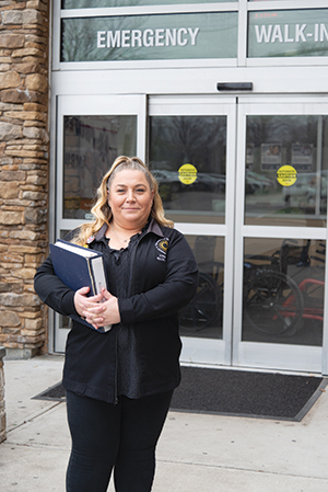 A mobile health employee woman stands in front of the Emergency Department