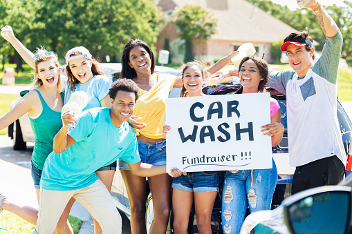 a group of kids holding a carwash