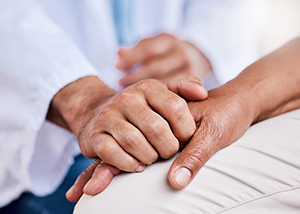 Caregiver's hand holds hand of patient